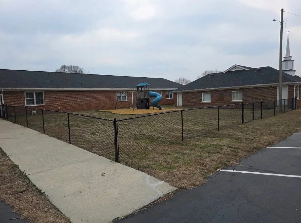 Black chain-link fence enclosing a commercial playground