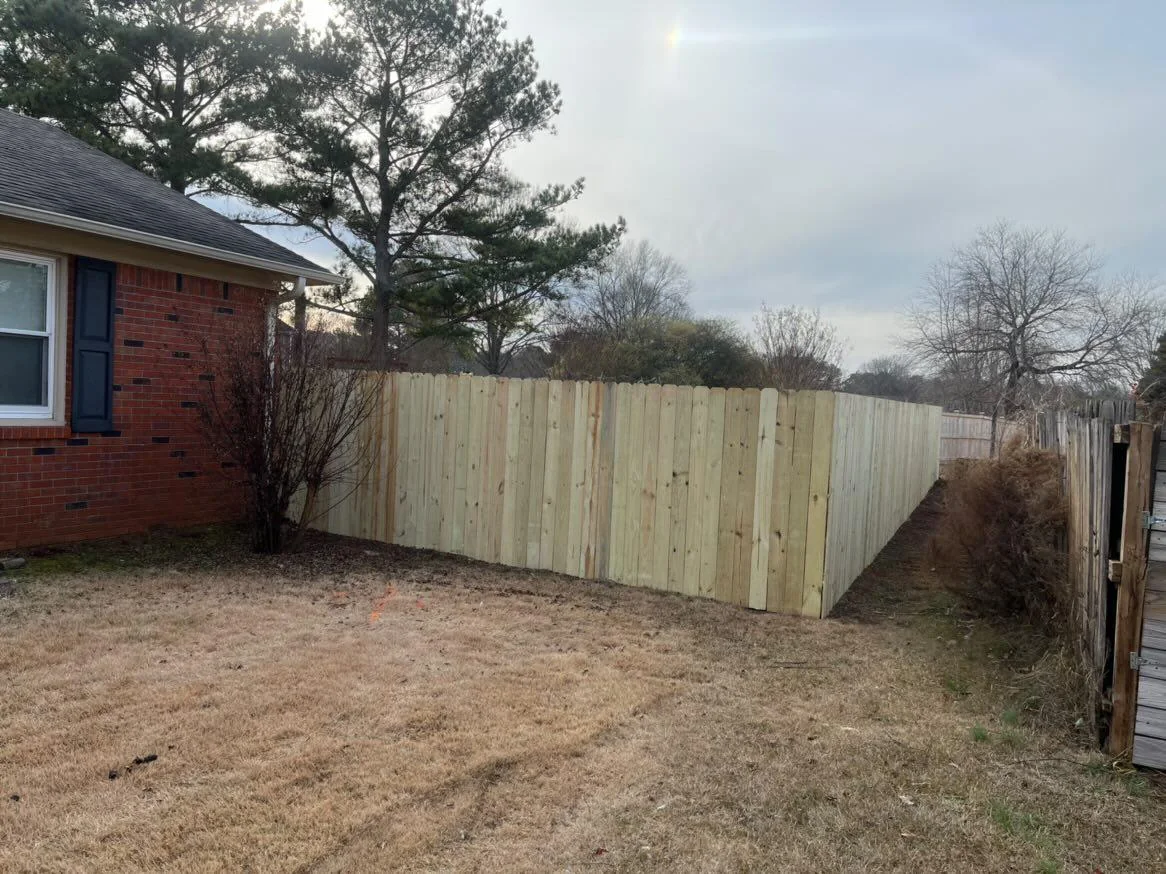 New wooden privacy fence beside a brick home